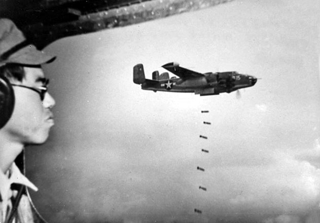 Certainly with mixed feelings, Japanese POW 2Lt Minoru Wada watches bombs fall on the Japanese 100th Infantry Division headquarters that he had just led the bombers to, Aug 9, 1945, Mindanao, Philippines