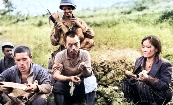 Japanese resistance fighters captured, Okinawa, Japan, Jun 1945; prisoner to the far left reading American propaganda literature [Colorized by WW2DB]