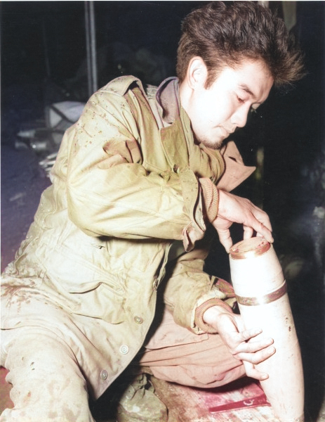 Japanese-American soldier of 552nd Field Artillery Battalion of US 442nd Regimental Combat Team fitting a base plate to a 105-mm shell filled with propaganda leaflets, France, date unknown [Colorized by WW2DB]