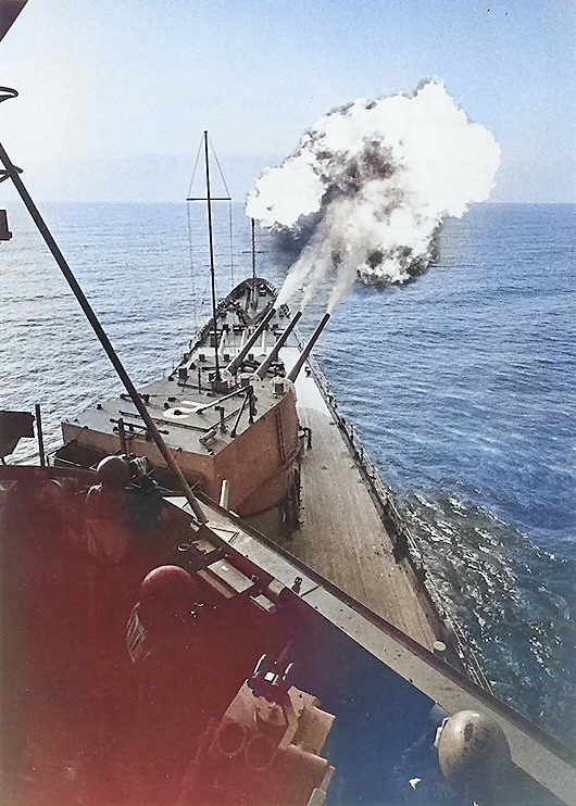 USS Canberra bombarding the coast of Vietnam, Mar 1967; note projectiles visible to the upper right of photograph [Colorized by WW2DB]