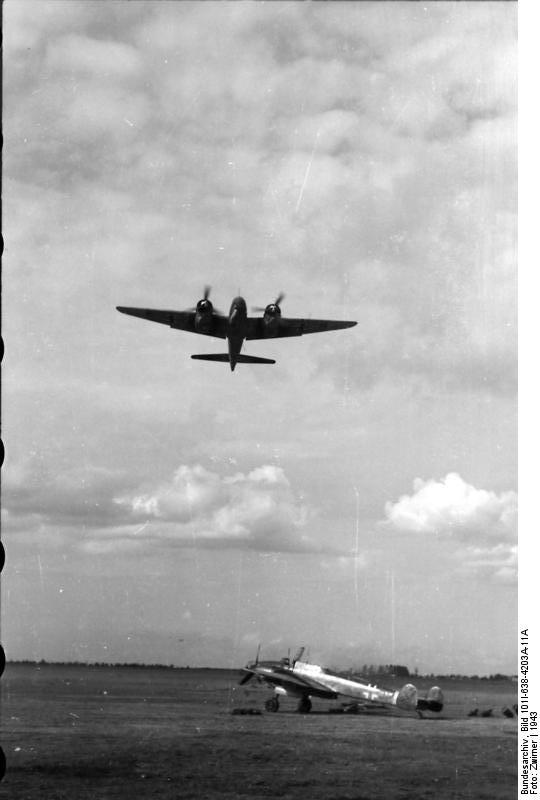 Ju 88 aircraft in flight in Germany, 1943; note Bf 110 fighter on ground