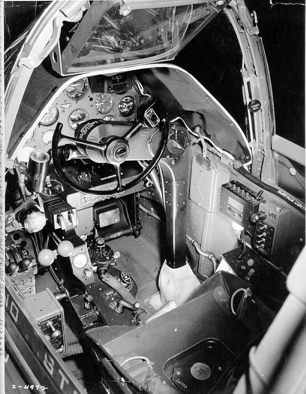 Close-up view of a P-38G Lightning aircraft cockpit, 23 Dec 1942; note the yoke rather than stick control and the bullet proof glass panel above the instrument panel. Photo 1 of 3.