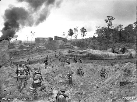 A Company of the Australian 2/23 Infantry Battalion advancing through wrecked oil storage tanks at tank hill, Tarakan, 1 May 1945