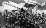 British Prime Minister Neville Chamberlain approaching press microphones at Heston Aerodrome near London, England, United Kingdom, upon his return from the Munich Conference, 30 Sep 1938. Note 2 Lockheed Super Electras.