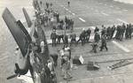 Crews move quickly to secure an F6F Hellcat as it hangs over the side of the training aircraft carrier USS Sable on Lake Michigan, United States, 1945.