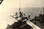 A crane hoists an F6F Hellcat after it nosed all the way over aboard the training aircraft carrier USS Sable on Lake Michigan, United States, 1945.