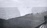 The splash close aboard the port side of USS Essex was caused by a Japanese D4Y Suisei dive bomber that crossed over the flight deck forward of the island before dropping into the sea, 19 Mar 1945