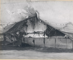 A sailor sitting in the starboard steering gear ram room of the USS Intrepid seen through a torpedo hole in the hull 15 feet below the waterline, taken as the water receded in Pearl Harbor Drydock #1, 26 Feb 1944.