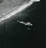 Submarine USS Harder with her bow against the reef off Woleai, Caroline Islands, 1 Apr 1944 as a rescue party went ashore to rescue aviator Ensign John Galvin on the beach. Note SOC Seagull seaplane.