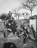 Soldiers of the 463rd Combat Engineers in France near the German border pause to observe Christmas the best way they could, 25 Dec 1944. Note K-ration cans as ornaments and three stacked M1 Garand rifles.