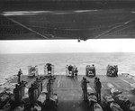 A burial at sea aboard the USS Hancock, 23 Jan 1945. These sailors died 4 days earlier when a TBM Avenger aircraft exploded just after landing. The explosion bent flight deck frame members that can be seen overhead.