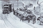 Canadian tank crew directs traffic around a disabled M4 Sherman tank while they install a new tread on a narrow road in Normandy, France, 1944. Note CMP ambulance and another CMP truck cab at right.