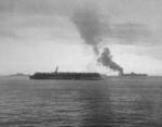 Smoke rising from the forward flight deck of the USS Randolph, San Pedro Bay, Leyte Gulf, Philippines, 7 Jun 1945 after a USAAF P-38 Lightning accidentally crashed into a group of parked airplanes.