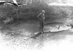 Member of US 5332nd Brigade (Provisional) Bill Hale on a log in a stream, a few miles south of Hsenwi, Burma, 1945