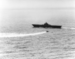 A TBM Avenger trailing smoke returning to the carrier USS Essex after being damaged by Japanese anti-aircraft fire during a strike on Minami Daito Jima in the Okinawa Operation, 28 Mar 1945.