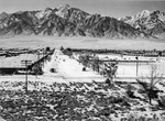 A view down 6th street at the Manzanar Relocation Center for deported Japanese-Americans, California, 1943. Barracks of Block 19 are on the left, the baseball field is on the right, and Mt Williamson is beyond.