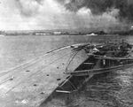 The capsized minelayer USS Oglala still tied to the dock after being sunk in the Japanese air attack on Pearl Harbor, Hawaii, mid-Dec 1941 photo. Note the checkerboard paint scheme of the harbor ferry Nihoa.