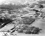 Aerial view of Marinship yard with six ways with tanker hulls under construction, eight tankers at the fitting out docks, and worker housing at the top, Sausalito, California, United States, 1944.