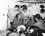 Two US Navy officers examining a Japanese officer’s sword on USS Nicholas, 27 Aug 1945 prior to entry into Tokyo Bay for the surrender ceremony a week later. Note other swords on the table in the foreground.