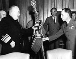 Captain Daniel Gallery presenting a German battle flag and flagstaff captured from submarine U-505 to Admiral Jonas Ingram. Secretary of the Navy James Forrestal is behind Admiral Ingram. 16 May 1945, Washington, DC.