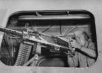 US Army combat photographer Staff Sergeant Andrew Yusko, Jr. posing with a M2 0.50 caliber machine gun aboard a B-24 Liberator bomber in Australia, 8 Jul 1944