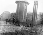 Men of US 101st Airborne Division walking past dead comrades, killed during Christmas Eve bombing of Bastogne, Belgium, 25 Dec 1944