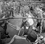 German soldiers made to load victims of Bergen-Belsen Concentration Camp onto a truck, Germany, 17 Apr 1945; note British troops in background with Sten submachine gun and Lee-Enfield rifles