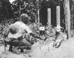 A Japanese Army soldier tending graves of fellow Japanese soldiers who were lost during the invasion, Malaya, circa Dec 1941-Feb 1942