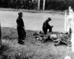 Cvilians placing flowers on the body of a dead American soldier, Carentan, France, mid-1944