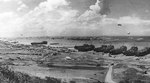 LSTs unloading at low tide in the Easy sector of Omaha Beach, Normandy, 28 Jun 1944, photo 1 of 2; note Gooseberry breakwater offshore