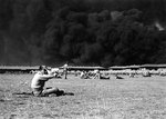 View of the Parade Ground at the Pearl Harbor Marine Barracks, between 0930 and 1130 on 7 Dec 1941, with smoke in the background rising from burning ships, photo 1 of 3