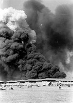 View of the Parade Ground at the Pearl Harbor Marine Barracks, between 0930 and 1130 on 7 Dec 1941, with smoke in the background rising from burning ships, photo 2 of 3