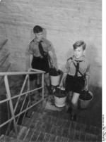 Hitler Youth members carrying buckets of coal in the staircase of an apartment building, Germany, date unknown