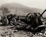 An American looking at a fallen German soldier near a destroyed German gun, Germany, 1945