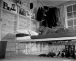 An African-American air cadet looking up at his collection of photos of his girl friends while he was studying on his cot, date unknown