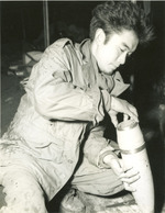 Japanese-American soldier of 552nd Field Artillery Battalion of US 442nd Regimental Combat Team fitting a base plate to a 105-mm shell filled with propaganda leaflets, France, date unknown