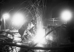 A burner in operation on the deck of a ship at night at Harland and Wolff