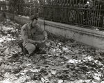 US Army photographer inspecting Japanese invasion money littered along a street in Rangoon, Burma, 1945