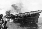 Franklin listing and afire after being hit by two bombs, off Japan, 19 Mar 1945; photograph taken from cruiser Santa Fe