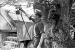 A German soldier spray painting a Jagdpanther tank destroyer for camouflage, France, Jun 1944