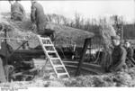 German troops building camouflage over a 10.5 cm K 35(t) field gun, France, Aug 1941