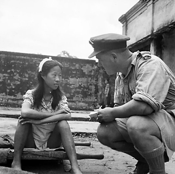 A Chinese girl from one of the Japanese Army's 'comfort battalions' talking to a British Army officer in Rangoon, Burma, 8 Aug 1945