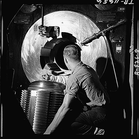 Sailor of American battleship New Jersey lowering the breech block of one of the ship's 16-in guns in preparation of loading a shell, Nov 1944