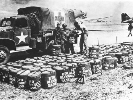 Blood and plasma moving from Britain to the front lines in France, 1944; note C-47 Skytrain aircraft and GMC CCKW 2 1/2-ton 6x6 short wheel-base truck