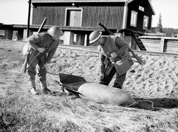 Two British soldiers inspecting an unexploded German bomb at the railway station at Grong, near Namsos, Norway, 30 Apr 1940; note Lee-Enfield No. 4 rifles