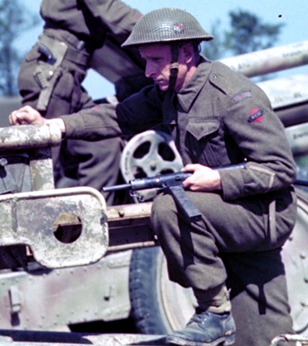 British soldier with Sten gun on a Soviet-built F-22 USV gun which had recently been captured from German troops, France, 1944